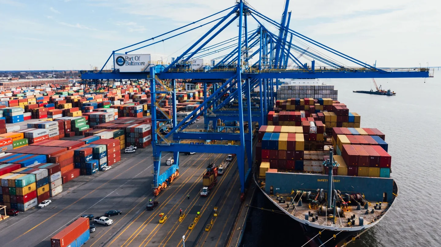 Blue cranes above a container terminal and a docked cargo ship