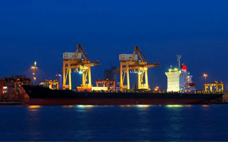 Illuminated cranes and a cargo ship in port at night